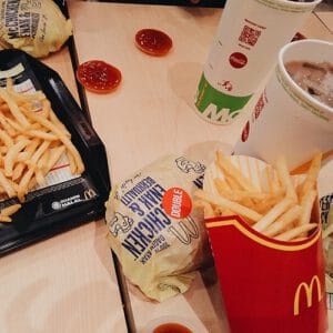 A picnic table covered with a McDonald's meal including fries, a burger and soda pop