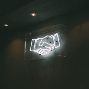 A white neon sign of two hands shaking