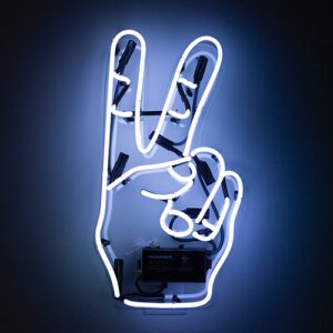 Blue neon light in a peace sign configuration lighting up a dark background