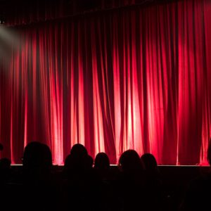 Closed red theatre curtains with audience in silhouette