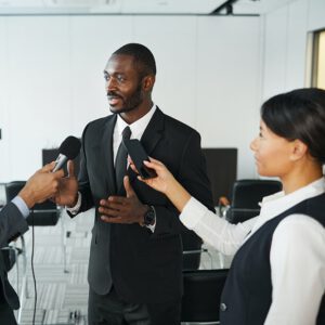 Man in black suit being interviewed