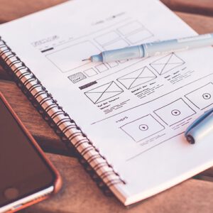 A sketchbook opened to a page with hand drawn wireframes